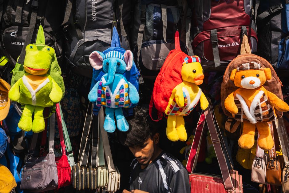 Vibrant plush toy backpacks hanging in a busy Colombo street market, Sri Lanka.